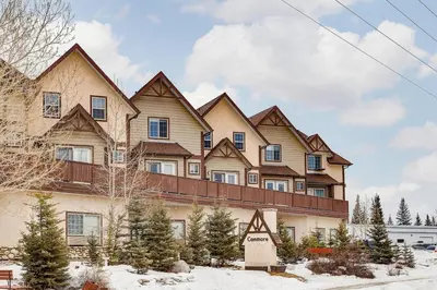 a large house with snow in front of it at Cozy Mountain View Condo Close to DT Canmore in Canmore