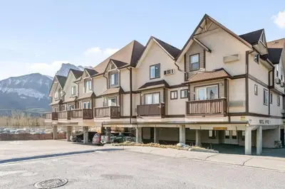 a large apartment building with mountains in the background at Cozy getaway for exploring Canmore and Banff in Canmore