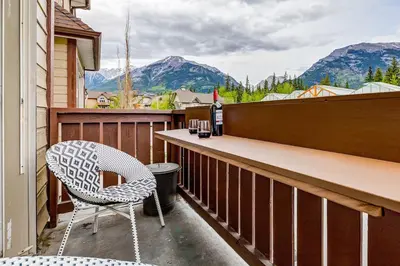 a balcony with a table and a chair and mountains at The Most Perfect Stay in Canmore with Mountain View in Canmore
