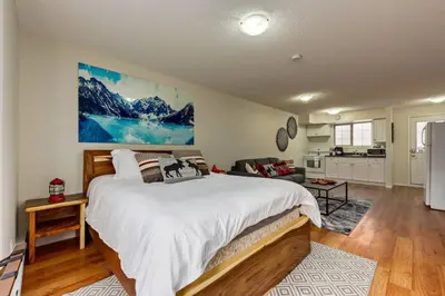 a bedroom with a large bed and a kitchen at Charming Condo In The Heart Of Canmore in Canmore