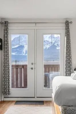a bedroom with a bed and a sliding glass door at Charming Condo In The Heart Of Canmore in Canmore