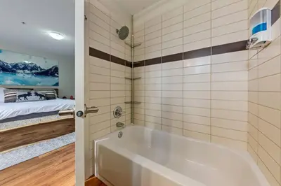 a bathroom with a tub and a bed in a room at Charming Condo In The Heart Of Canmore in Canmore