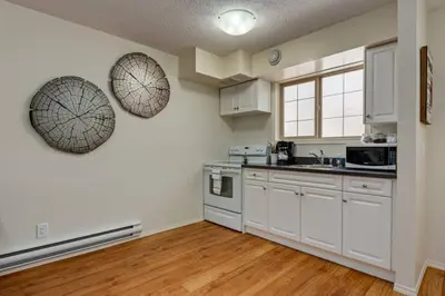 a kitchen with white cabinets and white appliances at Charming Condo In The Heart Of Canmore in Canmore