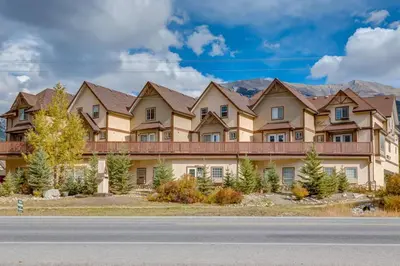 a large house with mountains in the background at Cozy Condo in the Heart of Canmore in Canmore
