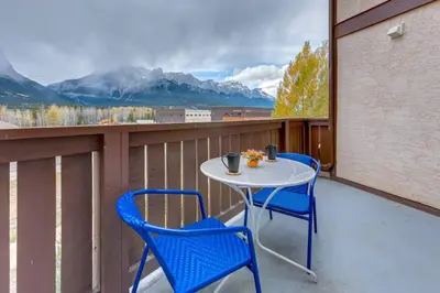 a table and chairs on a balcony with a view at Cozy Condo in the Heart of Canmore in Canmore