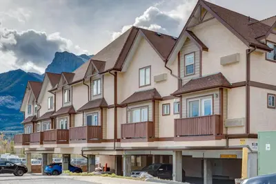 a large building with cars parked in a parking lot at Stylish Getaway in the Heart of Canmore near Banff in Canmore