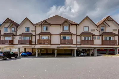 a large apartment building with balconies and cars parked in a parking lot at Delightful 2BR Mountain Escape in Canmore in Canmore