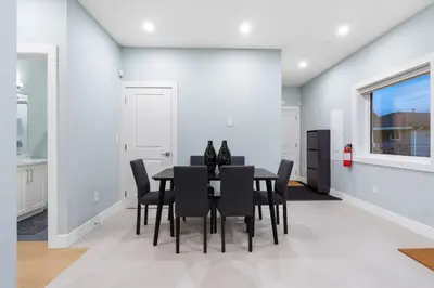 a dining room with a black table and chairs at Modern 6BR Home - Perfect for Groups & Families in Vancouver