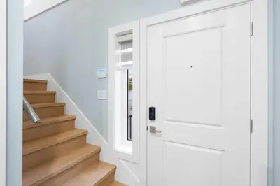a white door in a white hallway with stairs at Modern 6BR Home - Perfect for Groups & Families in Vancouver