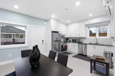 a kitchen with white cabinets and a black table at Modern 6BR Home - Perfect for Groups & Families in Vancouver