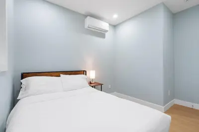 a bedroom with a white bed and a white wall at Modern 6BR Home - Perfect for Groups & Families in Vancouver