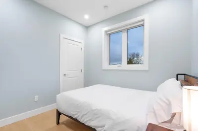 a white bedroom with a bed and a window at Modern 6BR Home - Perfect for Groups & Families in Vancouver
