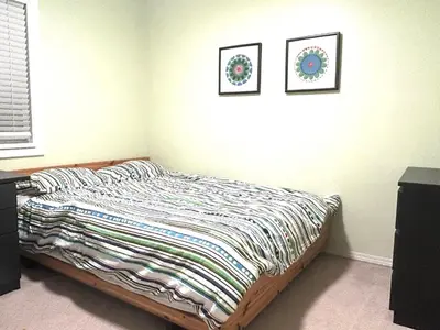 a bed in a bedroom with two pictures on the wall at Luxury & Spacious three bedrooms House Near Coquitlam Town Centre in Coquitlam