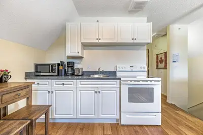 a kitchen with white cabinets and a white stove top oven at Traveler Friendly Canmore Condo Close to Banff in Canmore