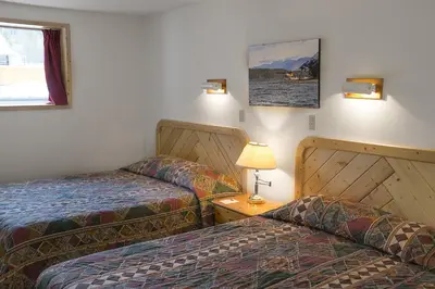 a hotel room with two beds and a table with a lamp at Northern Rockies Lodge in Muncho Lake