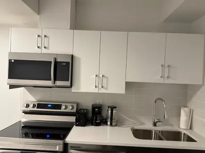 a kitchen with white cabinets and a sink and a microwave at Peace Haven in Edmonton