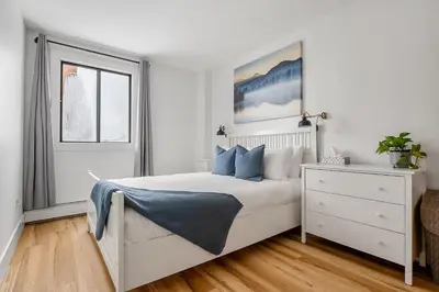 a white bedroom with a bed and a window at Peaceful DT Condo, Saddledome, HeatedParking in Calgary