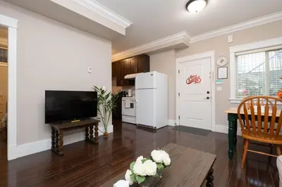 a kitchen and living room with a table and a television at Cozy 3 BR Suite Ideal for Families and Groups in Vancouver