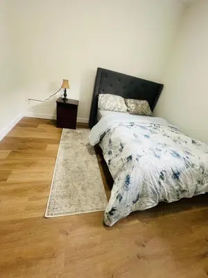 a bedroom with a bed with a black headboard and a rug at West Edmonton- Rose in Edmonton