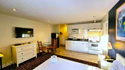 a kitchen with white cabinets and a table in a room at Cloud 9 Inn in Whitecourt