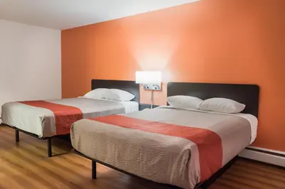 two beds in a room with orange walls at Motel 6-Fort St. John, BC in Fort Saint John