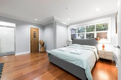 a bedroom with a large bed and a large window at Luxury 1200 squft 2BR Shaughnessy Suite Near YVR & DT in Vancouver