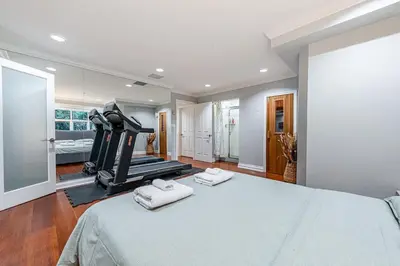 a bedroom with a large bed with a treadmill at Luxury 1200 squft 2BR Shaughnessy Suite Near YVR & DT in Vancouver