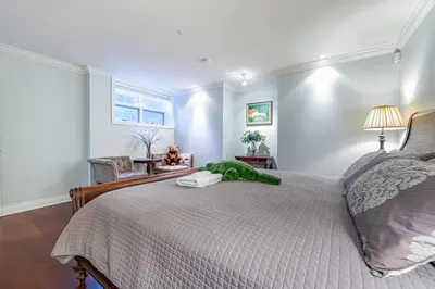 a bedroom with a bed with a green stuffed animal on it at Luxury 1200 squft 2BR Shaughnessy Suite Near YVR & DT in Vancouver
