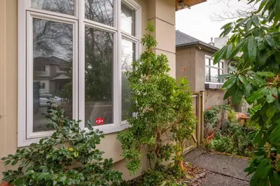 a window on a house with plants on the side at Comfort Spacious 2-BR Suite in Arbutus in Vancouver