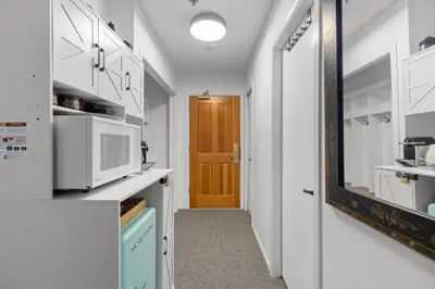 a kitchen with white cabinets and a brown door at 1BR | Greystone Lodge | Ski in / Ski out | Pool & Hot Tub | Epic Locations in Whistler