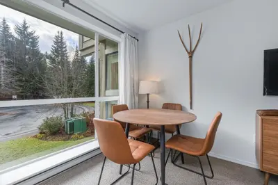 a dining room with a table and chairs and a window at 1BR | Greystone Lodge | Ski in / Ski out | Pool & Hot Tub | Epic Locations in Whistler