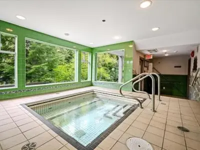 a large bathroom with a swimming pool with green walls at 1BR + Sofa Bed | Greystone Lodge | Ski in / Ski out | Pool & Hot Tub | Epic Locations in Whistler