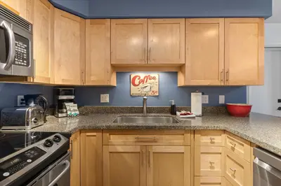 a kitchen with wooden cabinets and a sink at 1BR + Sofa Bed | Greystone Lodge | Ski in / Ski out | Pool & Hot Tub | Epic Locations in Whistler