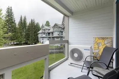 a balcony with chairs and a fan on a house at 2BR + Sofa Bed | Greystone Lodge | Ski in / Ski out | Split home living | Pool & Hot Tub in Whistler