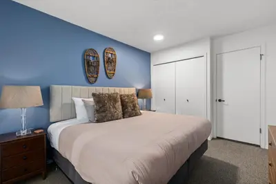 a bedroom with a large bed with a blue wall at 2BR + Sofa Bed | Greystone Lodge | Ski in / Ski out | Split home living | Pool & Hot Tub in Whistler