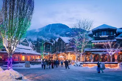 a group of people walking around a town with christmas lights at 2BR + Sofa Bed | Greystone Lodge | Ski in / Ski out | Split home living | Pool & Hot Tub in Whistler