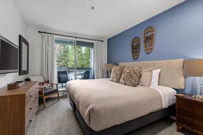 a bedroom with a large bed and a tv at 2BR + Sofa Bed | Greystone Lodge | Ski in / Ski out | Split home living | Pool & Hot Tub in Whistler