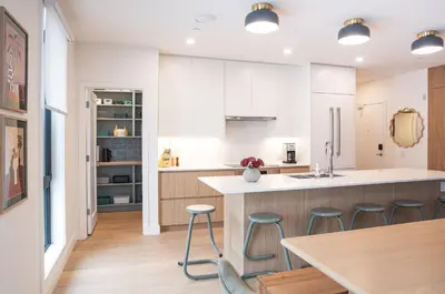 a kitchen with white cabinets and a table and stools at Revel and Rest by Revelstoke Vacations in Revelstoke