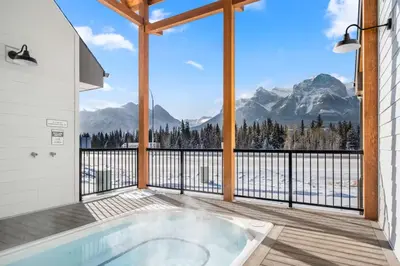 a hot tub on a deck with a view of mountains at Skyridge Mountain Retreat 4BR with BBQ Near Banff in Canmore