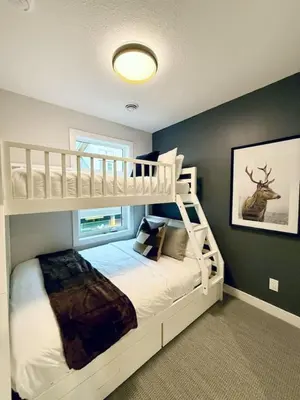 a bedroom with a white bunk bed with a ladder at Mountain Retreat with Views and Hot Tub Near Banff Gates in Canmore