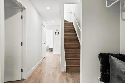 a hallway with white walls and wooden stairs at 3BR Rockies Haven Near Banff with Private Patio in Canmore