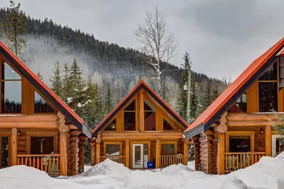 a log cabin in the snow with mountains in the background at Beautiful Cottage In The Heart Of The Rockies in Golden