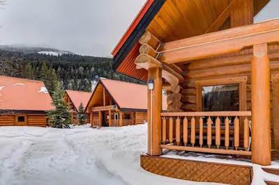 a log cabin in the snow with a porch at Beautiful Cottage In The Heart Of The Rockies in Golden