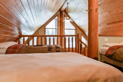two beds in a room with a large window at Authentic, Timber Log Cabin Perfect for Groups in Golden