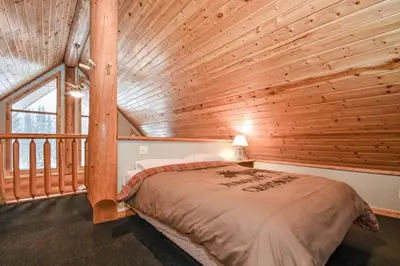 a bed in a room with a wooden wall at Authentic, Timber Log Cabin Perfect for Groups in Golden