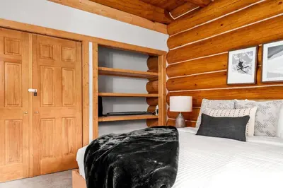 a bedroom with a bed and a wooden wall at Rustic Cabin Hideaway with BBQ Fire Pit and Mtn Views in Golden