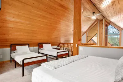 two beds in a room with wooden walls at Rustic Cabin Hideaway with BBQ Fire Pit and Mtn Views in Golden