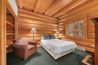 a bedroom with a bed and a chair in a log cabin at Rustic Chalet Perfect Getaway for Groups in Golden