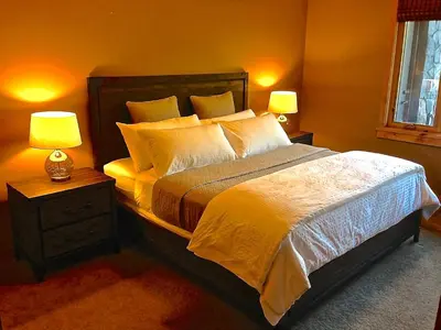 a bedroom with a bed with two lamps on tables at Luxury Canmore Vacations in Canmore
