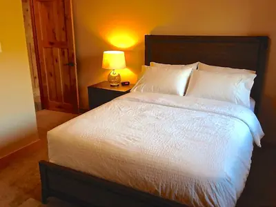 a bedroom with a white bed with a lamp on a table at Luxury Canmore Vacations in Canmore